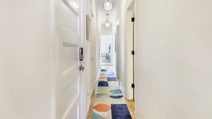Un corridoio con pareti bianche, una tappezzeria colorata e un lampadario.