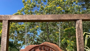 Une enseigne en bois, ornée d’un motif de boussole et portant l’inscription « Lost Compass Cabanas », est fixée sur un cadre métallique.