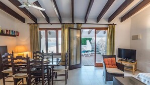 Ein geräumiger Wohnbereich mit Esstisch, Stühlen, einer Couch, einem Fernseher und einem Balkon mit Gartenmöbeln.