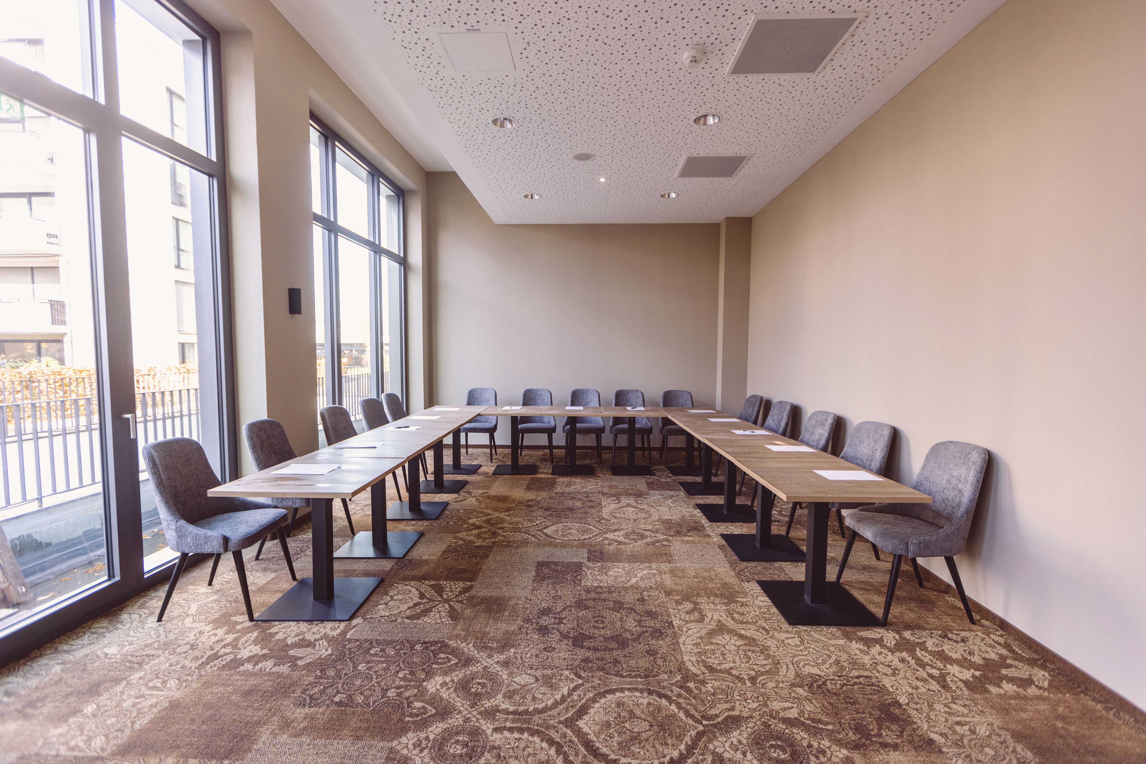 Un salón de conferencias con una larga mesa, sillas y ventanas amplias.