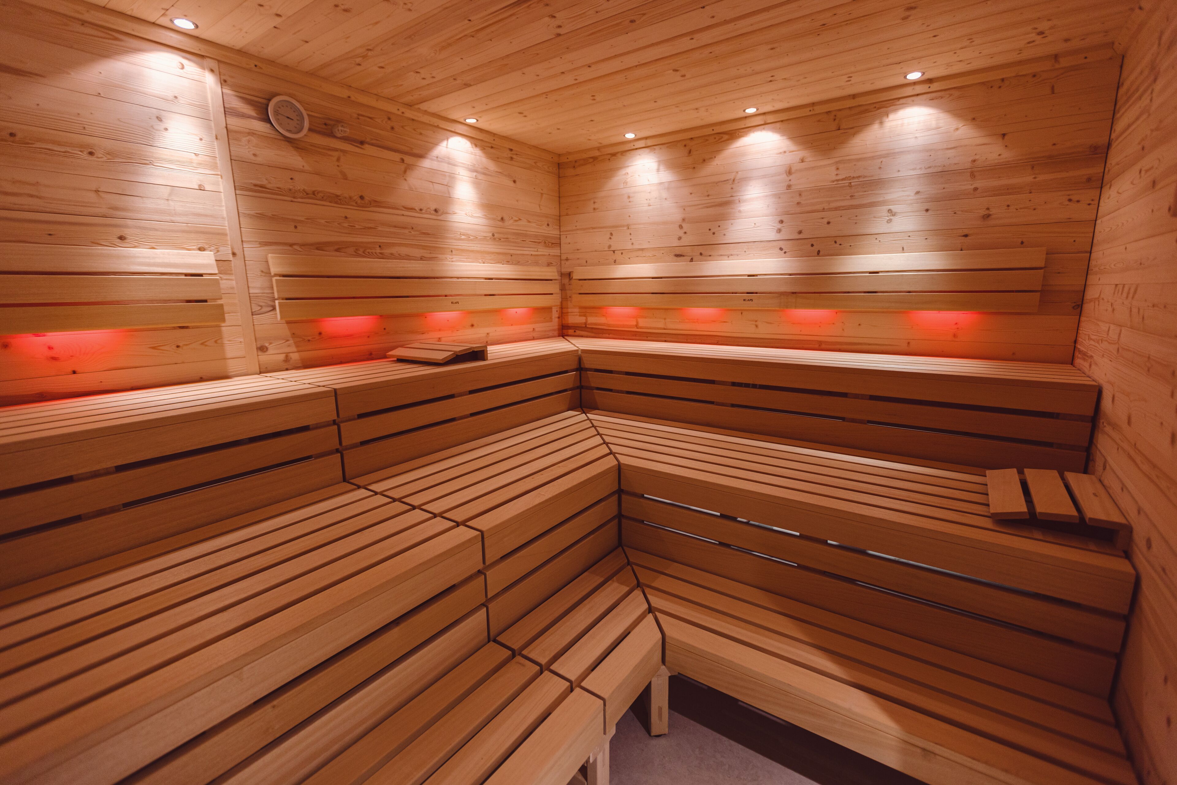 Uma sauna com bancos de madeira e iluminação vermelha.