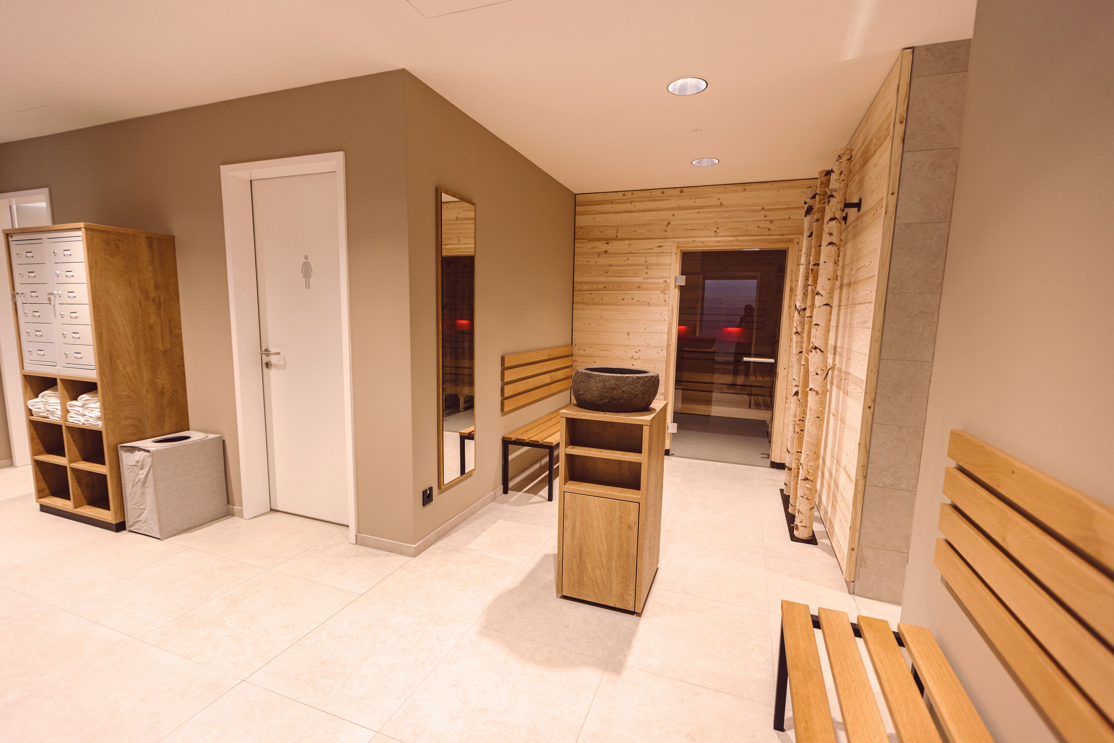 Une salle de bain moderne avec un banc en bois, un lavabo doté d’une grande cuve et un miroir.