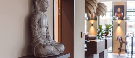 Una estatua de Buda sobre una estantería en un espacio interior moderno con una zona de recepción y vistas a la ciudad.