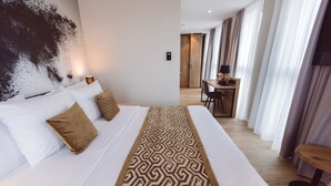 A hotel room with a large bed, a patterned runner, and a desk with a chair. - Hotel Libertas elements pure (Merzhausen)