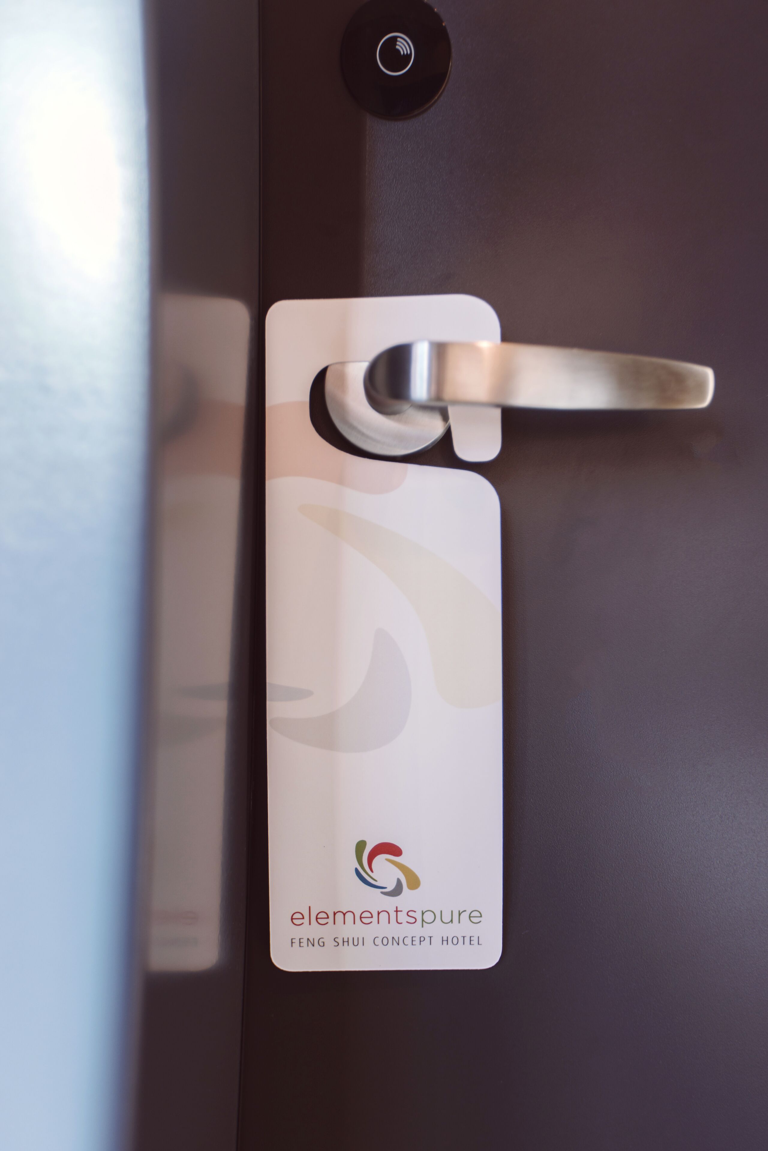 A hotel room door with a metal handle and a white card with the hotel name and logo.