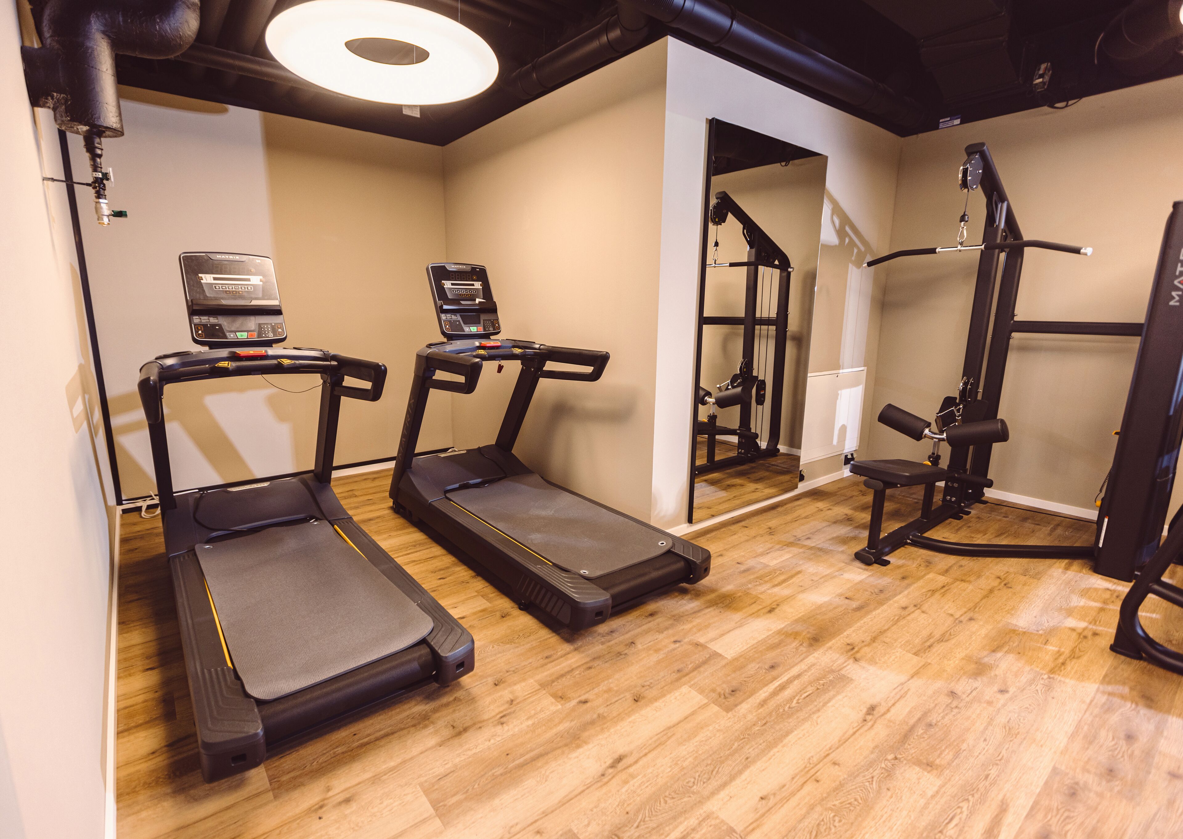 Une salle de sport à domicile équipée de tapis de course, d’un banc de musculation et d’un miroir.
