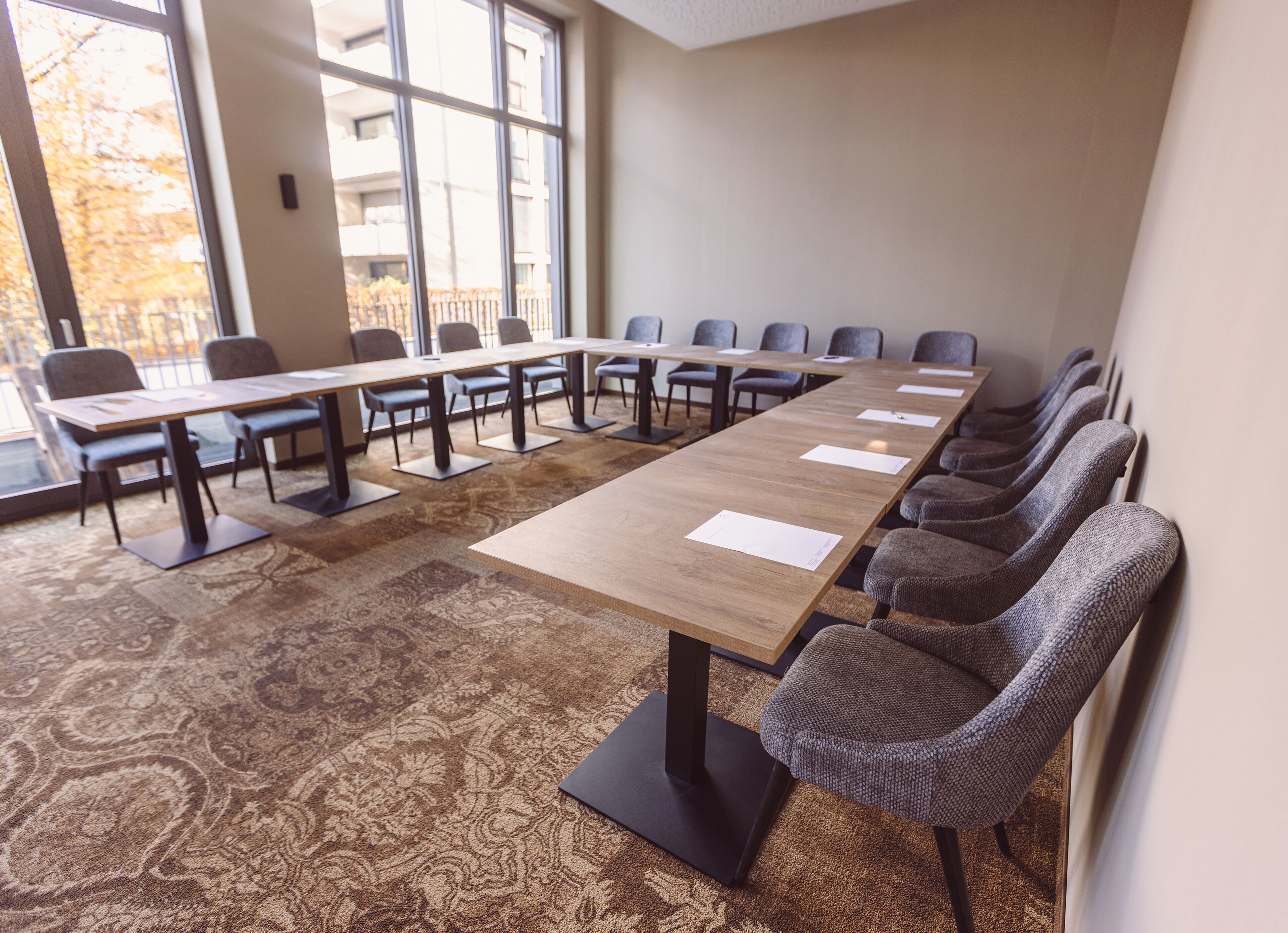 A conference room with a long table, chairs, and a patterned carpet.