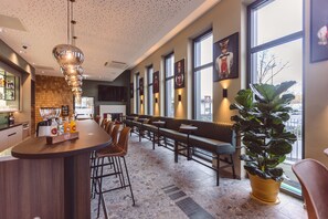 Ett modernt barområde med en bardisk, sittplatser och en stor krukväxt.