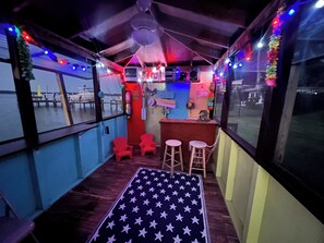 Eine gemütliche Bar mit Holzboden, roten Stühlen, Hockern und einem Teppich mit Sternenmuster.