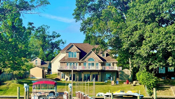 Une maison avec un quai et des bateaux, entourée d’arbres.