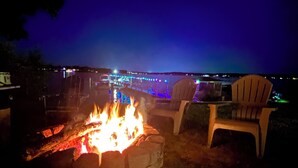Un foyer avec des chaises, une vue sur un quai illuminé et une étendue d’eau.
