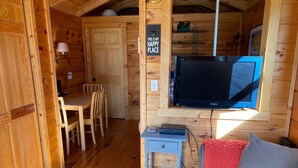 En mysig stuga med en matplats, en tv och en soffa.