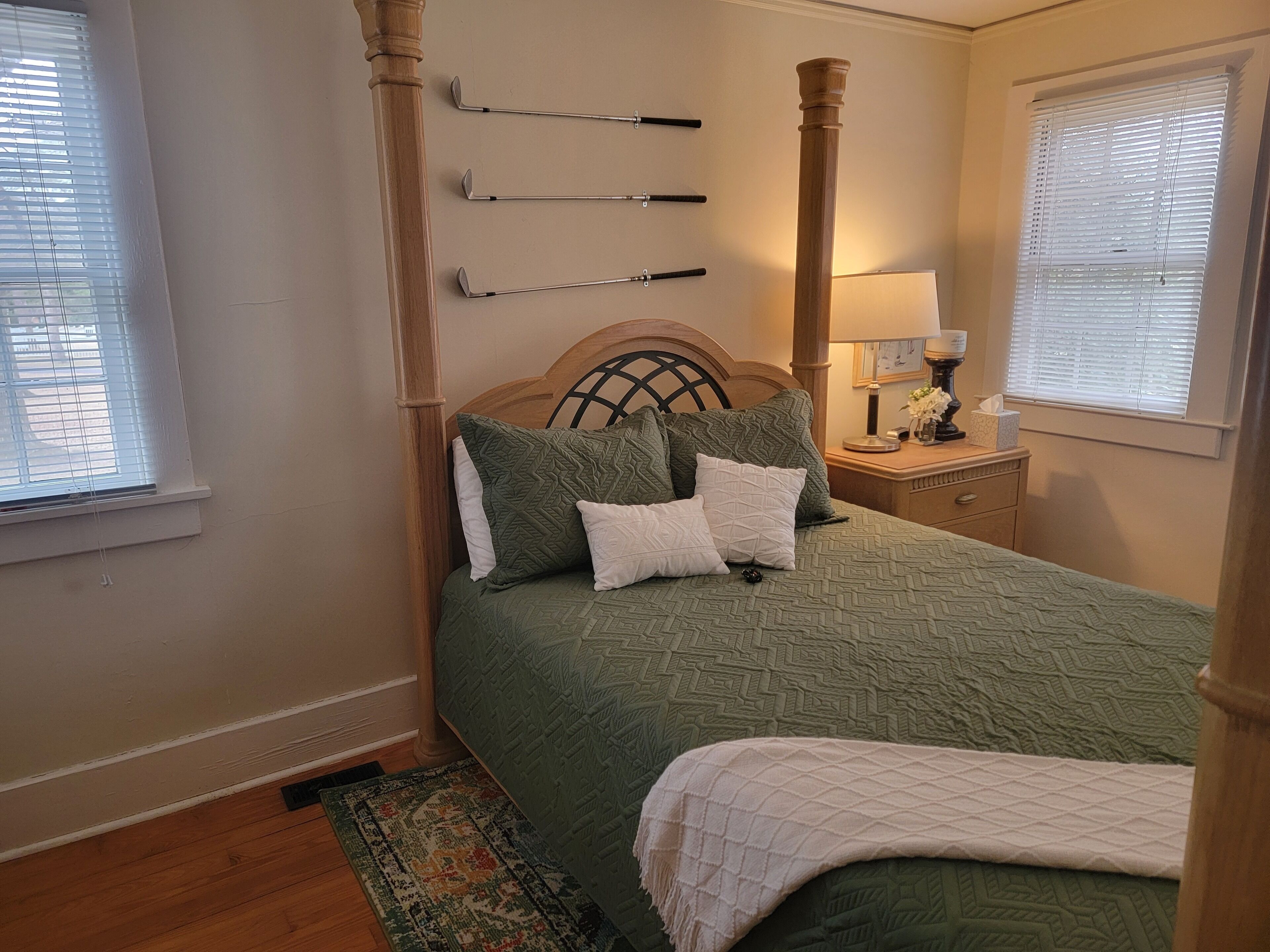 A bedroom with a bed, a nightstand, a lamp, and a window with blinds.
