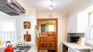 Una cocina moderna con armarios blancos, un hervidor rojo y un microondas.