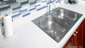 Een keuken met een magnetron, spoelbak en een bord met de tekst 'Pura Vida Costa Rica'.