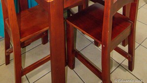 Een eettafel gedekt met borden, glazen en een fles, omringd door houten stoelen.