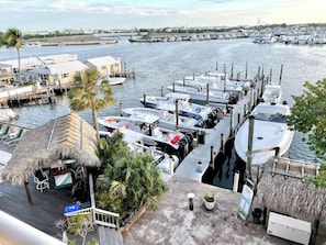 A marina with boats docked, a thatched-roof structure, and a view of the water.