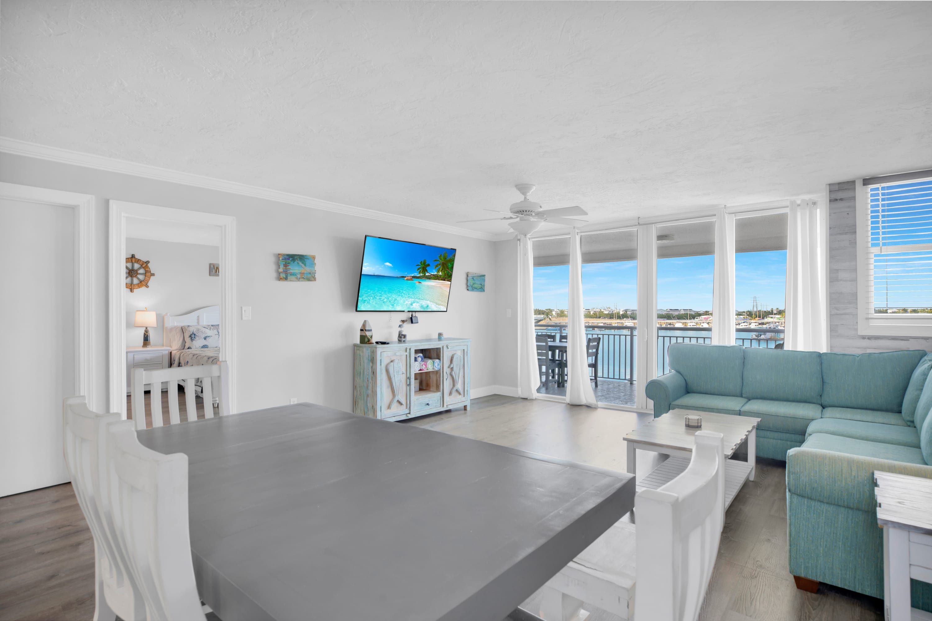 A spacious living area with a balcony, a dining table, and a blue sofa.