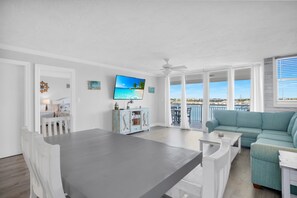A spacious living area with a balcony, a dining table, and a blue sofa.