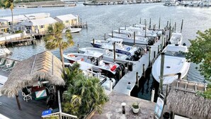 A marina with boats docked, a thatched-roof structure, and a view of the water. - Waterfront Dock Pool Condo Near Duval St Pet OK (Key West)