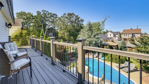 A wooden deck with a pool, lounge chairs, and a view of neighboring houses. - Near Yale & Lighthouse Point Beach: Home w/ Pool! (New Haven)