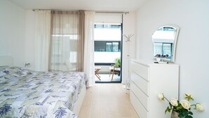 Une chambre à coucher avec un lit, une commode, un miroir et une vue sur un balcon.