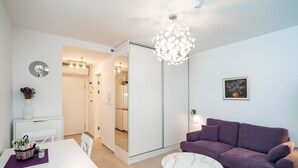 Un salon moderne avec un canapé violet, une table basse blanche et un coin repas comprenant une table et des chaises blanches.