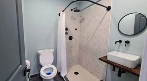 Bathroom features a toilet, shower, and sink with a geometric tile design.