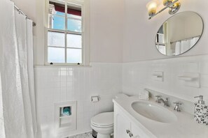 Een badkamer met toilet, wastafel, spiegel en raam.