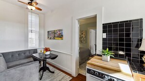 A compact kitchen with a stove, a dining table, and a sofa. - Lanaux Mansion - Beth's Escape with Courtyard Balcony (New Orleans)