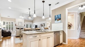 A spacious kitchen with a large island, wooden flooring, and pendant lighting. - Spacious & Private Getaway Near Downtown Raleigh! (Raleigh)