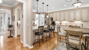 A spacious kitchen with wooden cabinets, a central island, and pendant lighting. - Spacious & Private Getaway Near Downtown Raleigh! (Raleigh)
