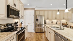 A kitchen with wooden cabinets, stainless steel appliances, a double sink, and pendant lighting. - Spacious & Private Getaway Near Downtown Raleigh! (Raleigh)