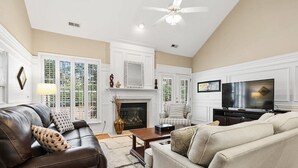A spacious living room with a fireplace, leather sofa, and a television. - Spacious & Private Getaway Near Downtown Raleigh! (Raleigh)