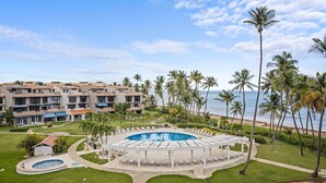 Un resort con piscina, palmeras y vista al mar.