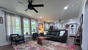 A spacious living room with a large, colorful rug, a dark leather sofa, and a ceiling fan. - The Fox Den, luxury home, just 2 minutes away from the iconic Bell Buckle Cafe. (Bell Buckle)