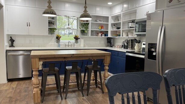 A modern kitchen with white cabinets, a wooden island, bar stools, and a stainless steel refrigerator. - The Fox Den, luxury home, just 2 minutes away from the iconic Bell Buckle Cafe. (Bell Buckle)