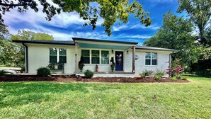 A single-story house with a front porch, a small garden, and a clear blue sky. - The Fox Den, luxury home, just 2 minutes away from the iconic Bell Buckle Cafe. (Bell Buckle)
