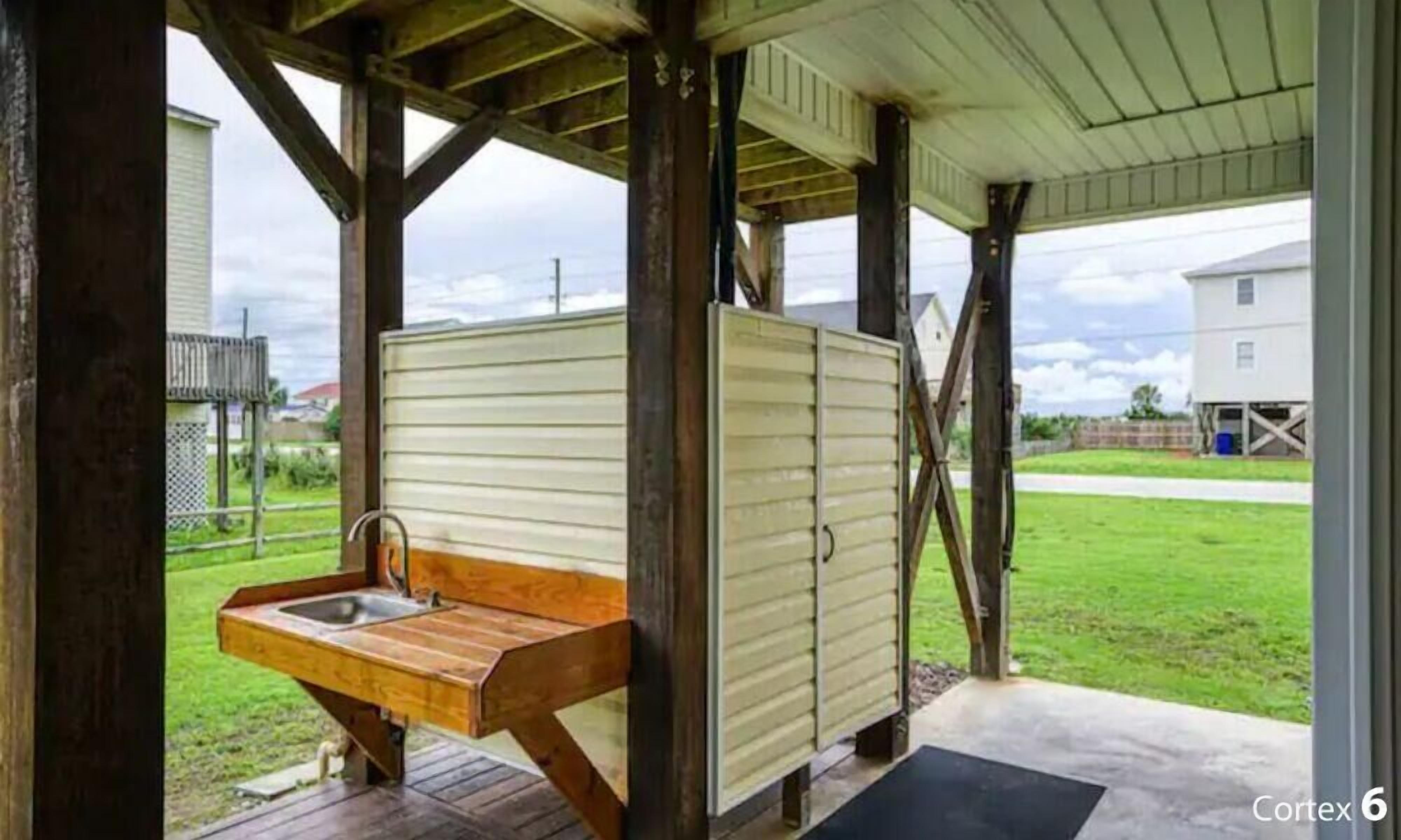 A covered outdoor area with a wooden bench and a sink.