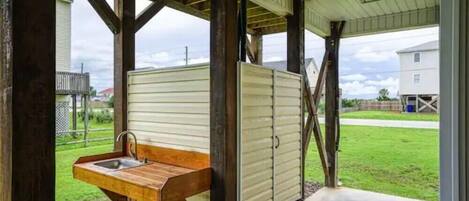 A covered outdoor area with a wooden bench and a sink.