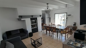 A spacious living area with a sofa set, a dining table, and a kitchen area with a coffee machine. - Breton house 400m from the beach (Crozon)