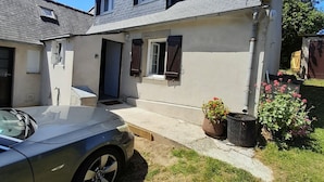 A two-story house with a grey roof, a small front porch, and a car parked in the driveway. - Breton house 400m from the beach (Crozon)