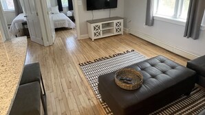 A modern living room with a flat-screen TV, a ceiling fan, and a wooden floor. - Close to everything (Newport)