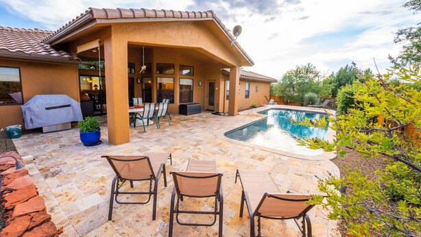 Un'area patio con piscina, mobili da esterno e un angolo barbecue.