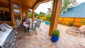Patio esterno con barbecue, tavolo da pranzo, sedie e piscina.