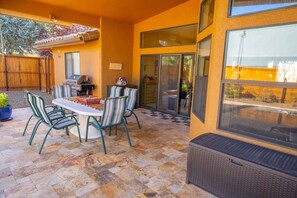 An outdoor patio with a dining table and chairs, a grill, and a large sliding glass door leading to a balcony. - Indian Cliffs Getaway ~ 3 bedroom with pool (Sedona)