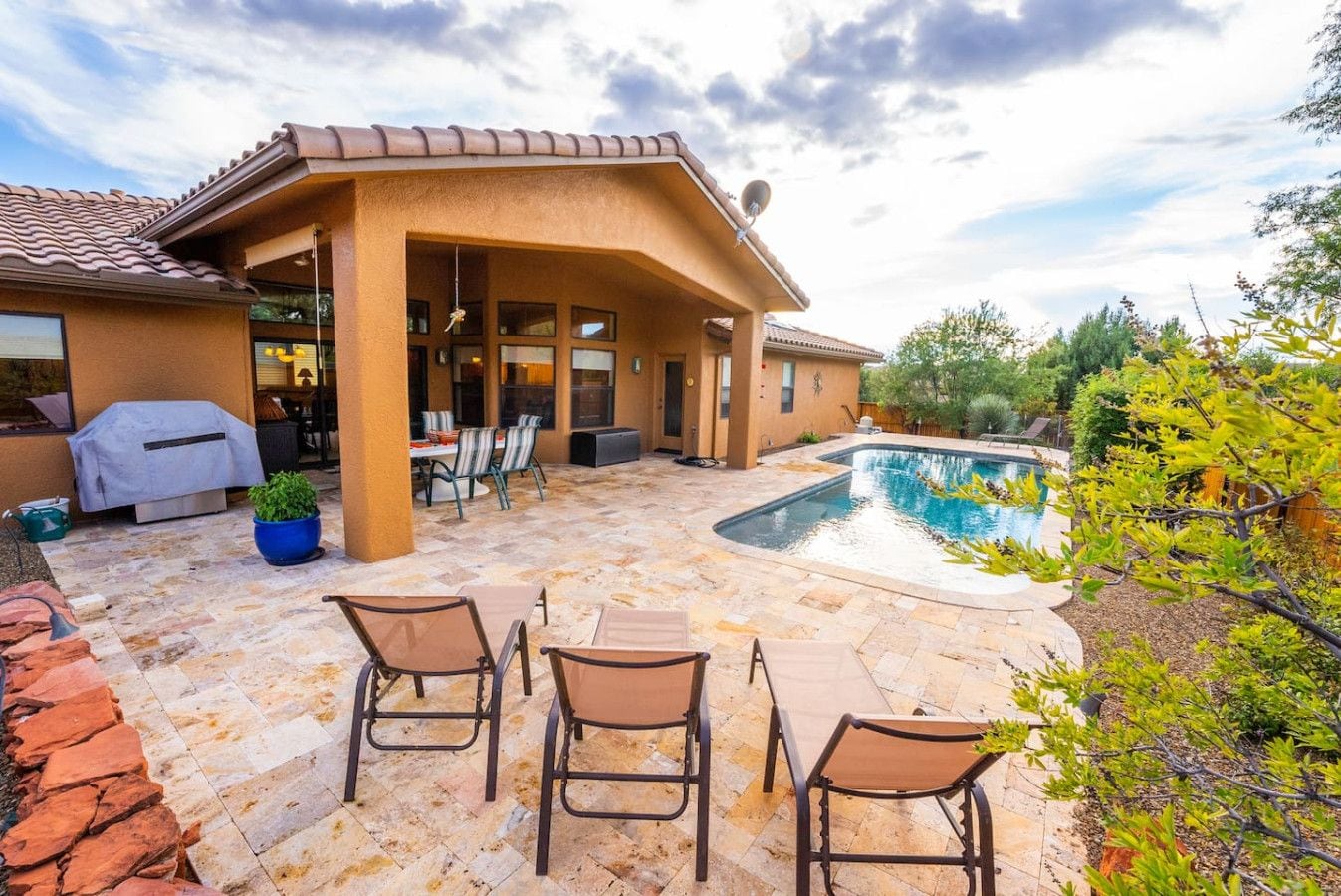 Ein Patio mit Pool, Sitzgelegenheiten im Freien und einer Grillstation.