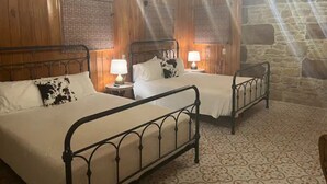 Ein Zimmer mit zwei Betten, Holzwänden, einer Steinwand und einem gemusterten Boden.