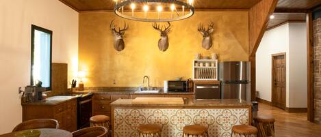 Une cuisine dotée d’un îlot central, d’un plafond en bois et d’un lustre.
