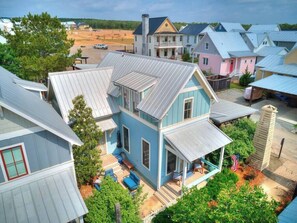 Une maison à deux étages avec un porche, une cour clôturée et une vue sur les maisons voisines.